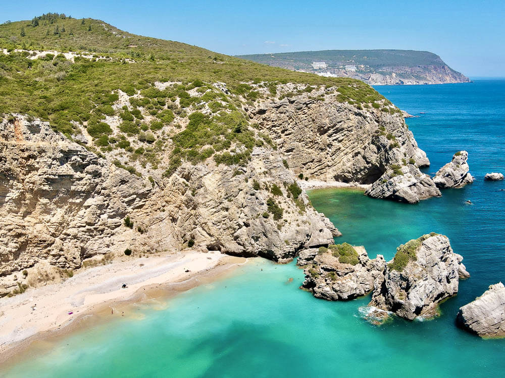 A beach in central Portugal, with rocky formations surrounding the white sands and crystal-clear waters.