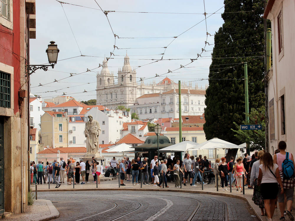 A diverse group of people walking together on a bustling street in Lisbon, Portugal.