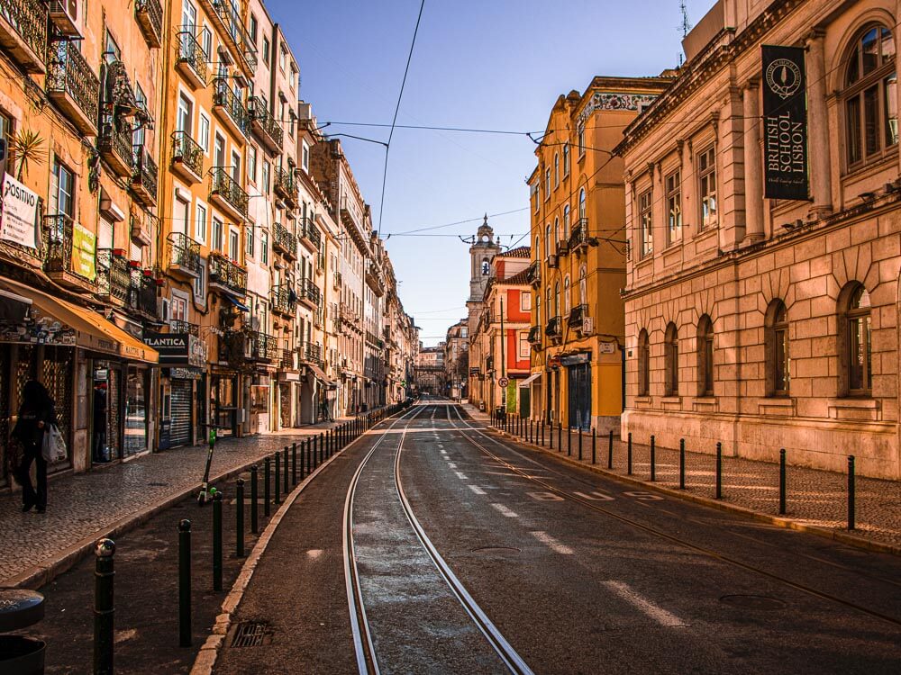 View of a street in Lisbon, lined with historical buildings in earthy tones. 