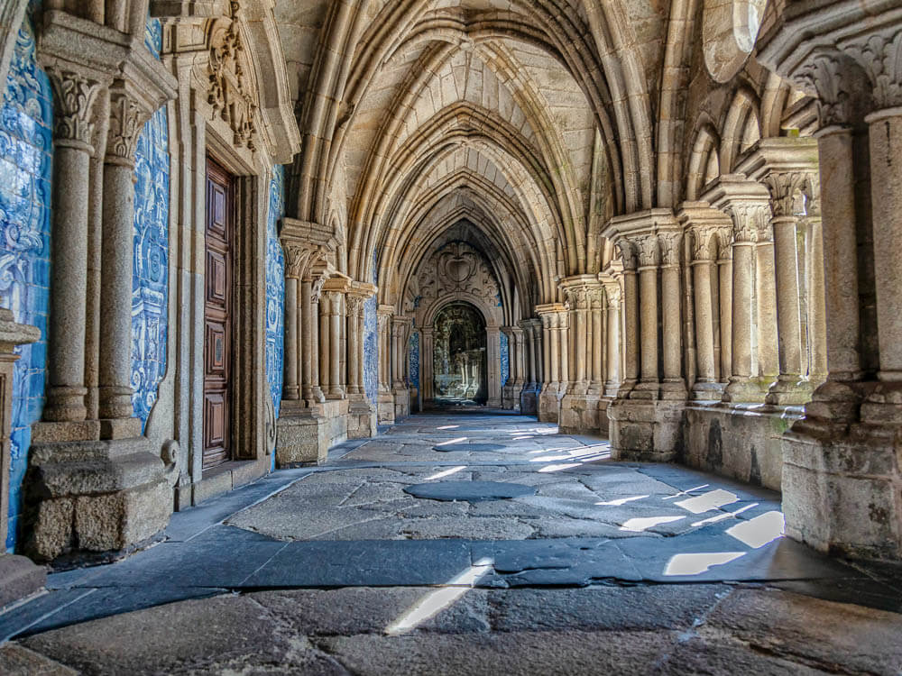 Interior of a gothic church in Porto with stone pillars, high ceilings and Portuguese tiles on the walls.