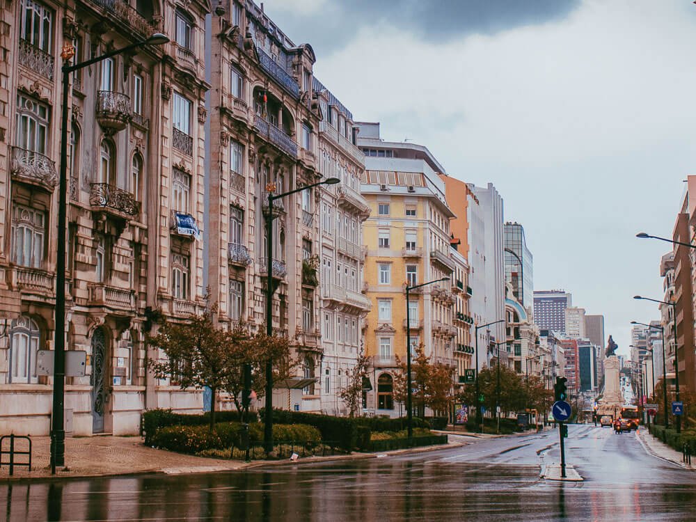 A rainy day on a street in Lisbon with buildings and cars.