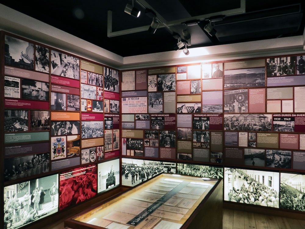 Exhibition at the Aljube Museum, with various photos telling the history of Portugal and an illuminated display in the center of the room.