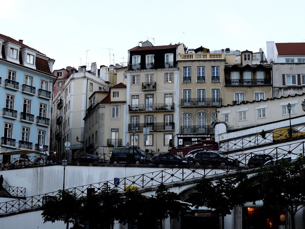 Historic buildings in the Bairro Alto, with cars parked on the street.