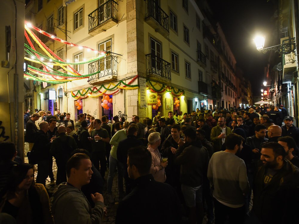 A crowd of people on a street in the Bairro Alto at night.