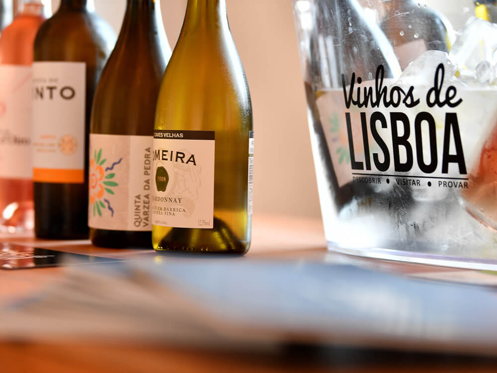 Four Portuguese wines on a counter. On the right side, a transparent bucket with ice and more wines, with "Wines of Lisbon" written in black.