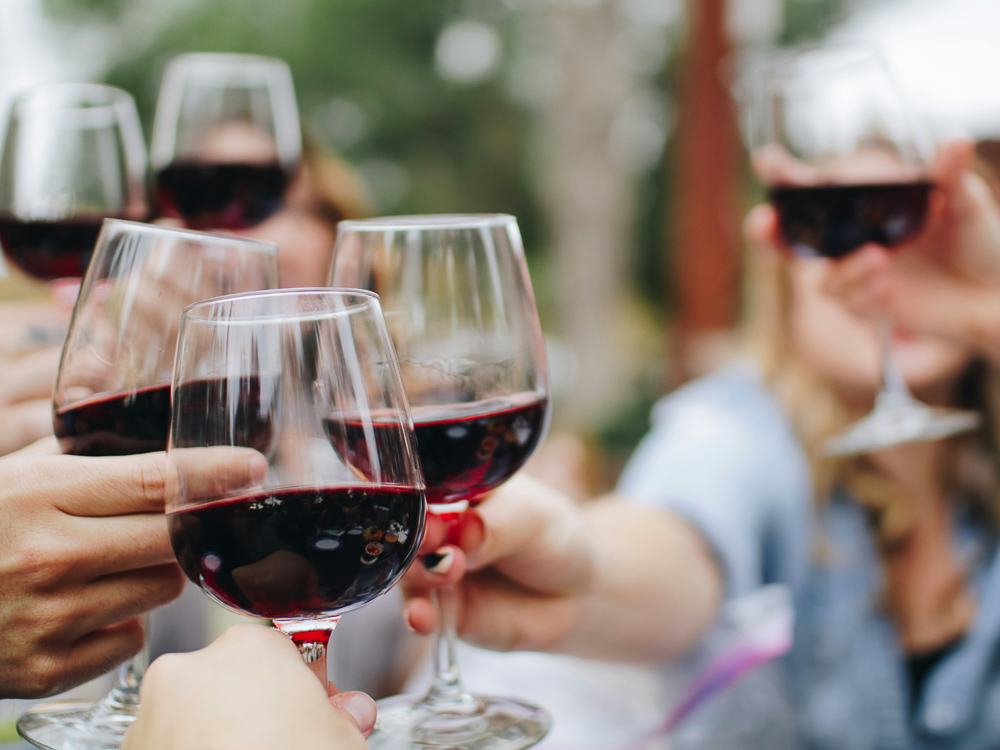 A group of people toasting with glasses of red wine.