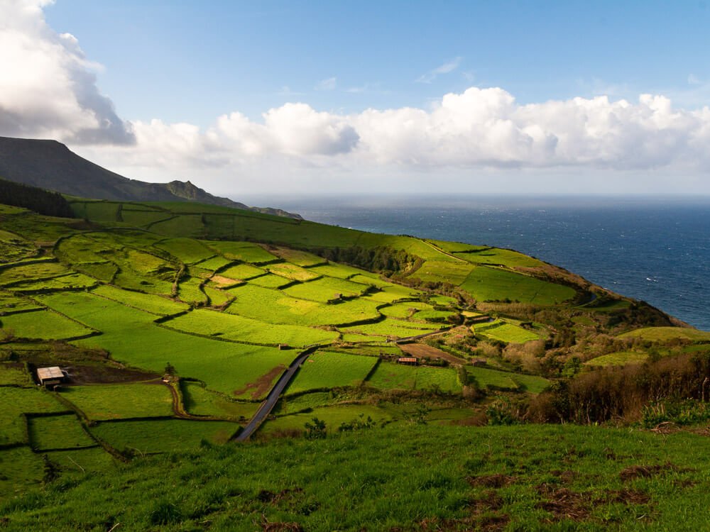 Aerial view of the Azores, with lots of greenery and the sea in the background.