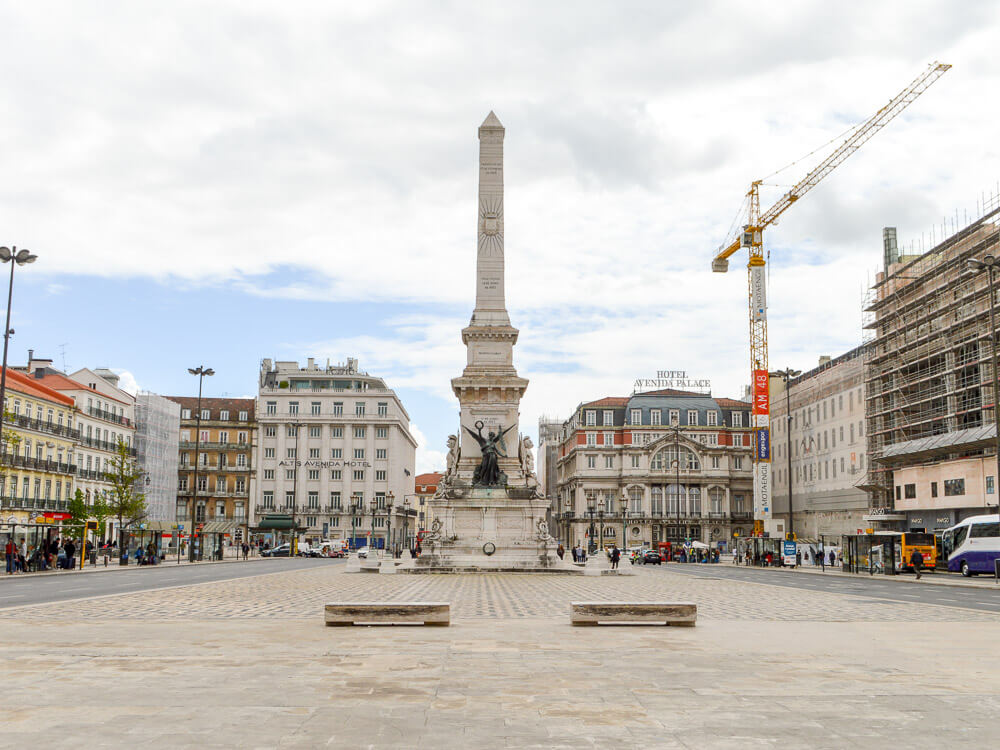 A central plaza in Lisbon with the Monument to the Restorers, surrounded by historic buildings and ongoing construction, showcasing the city's blend of old and new.