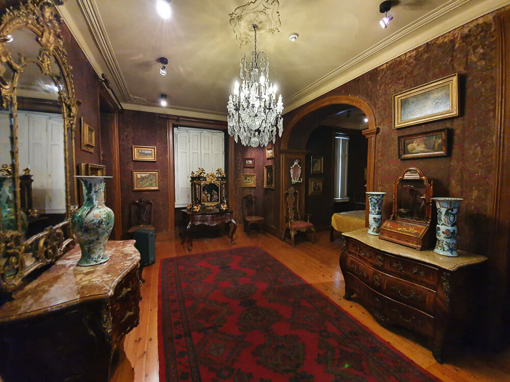 Luxurious room in a historic house, featuring antique furniture, decorative vases, and a chandelier.