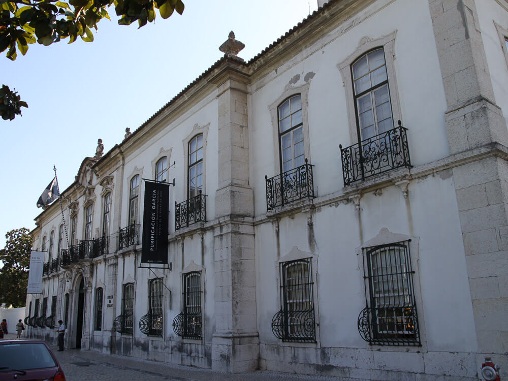 A historic white building with ornate iron balconies, housing the Lisbon Museum.
