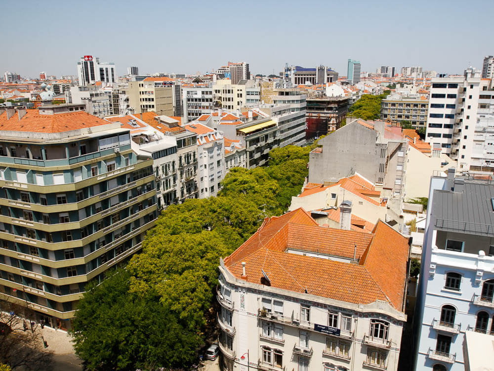 An aerial view of Lisbon featuring a mix of modern and traditional buildings with red-tiled roofs.