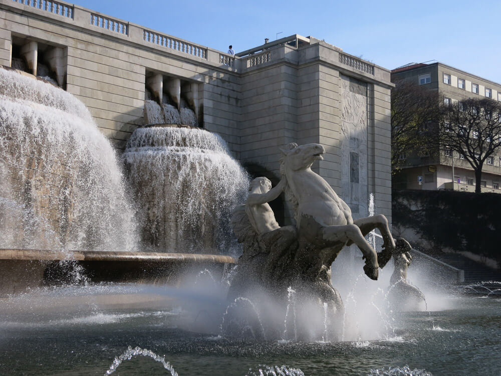 A grand fountain with sculptures of horses and human figures, surrounded by cascading water.