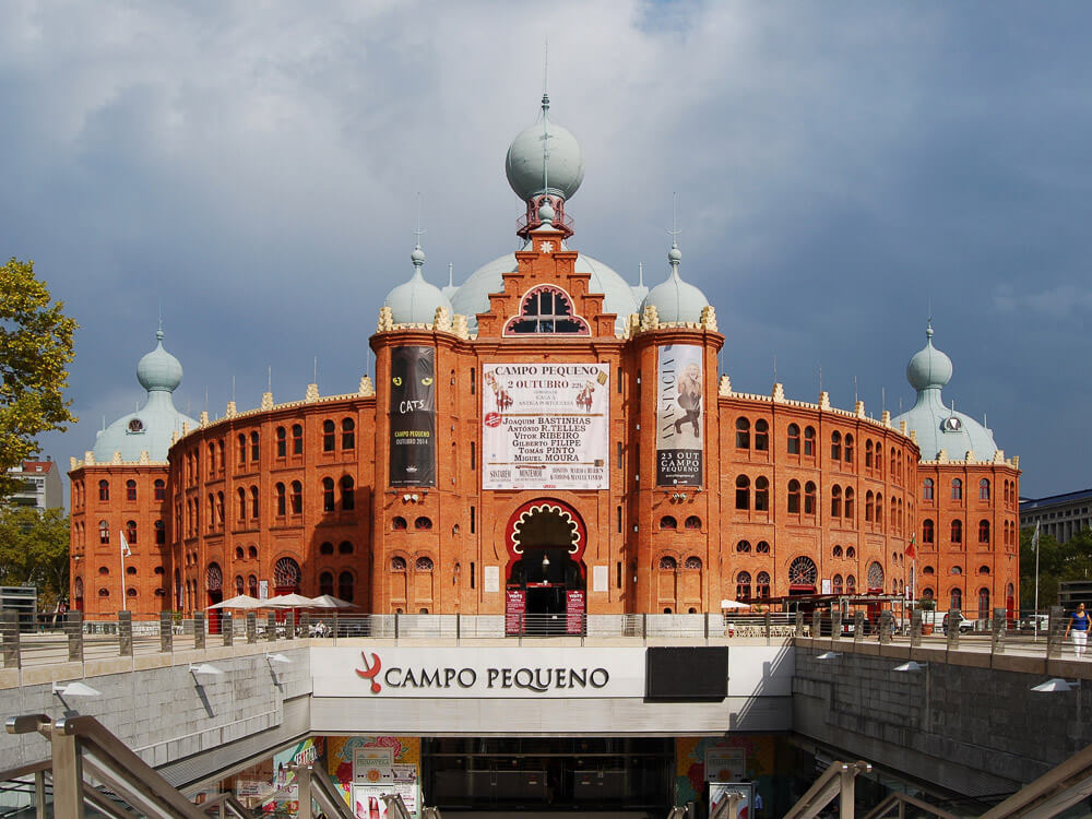 A large, red-brick building with distinctive domes and arches. It's Arena Campo Pequeno, a bullfighting arena in Lisbon.