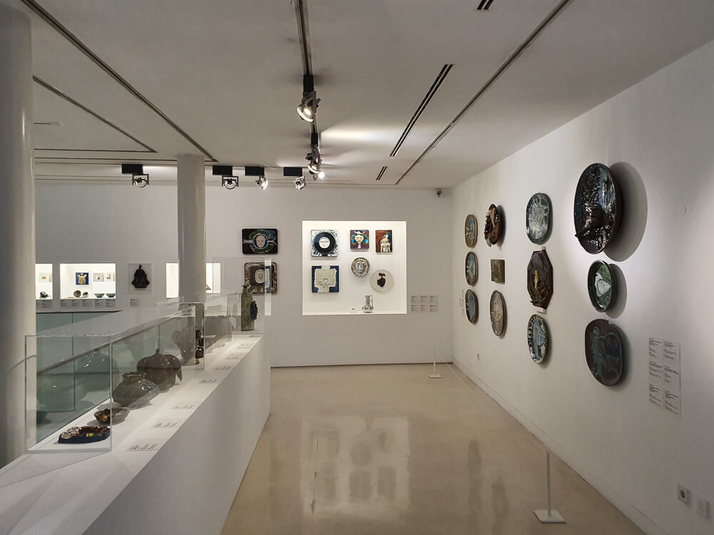 Museum display featuring a variety of ceramic plates and artifacts on white walls.