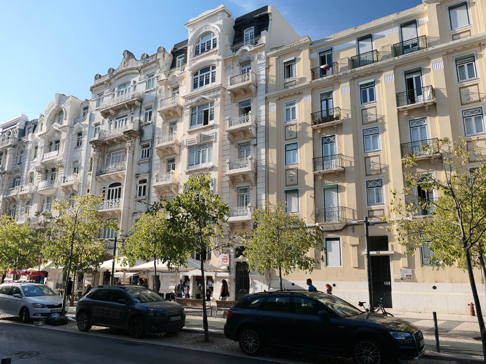 Street view of elegant residential buildings with detailed facades and small balconies.