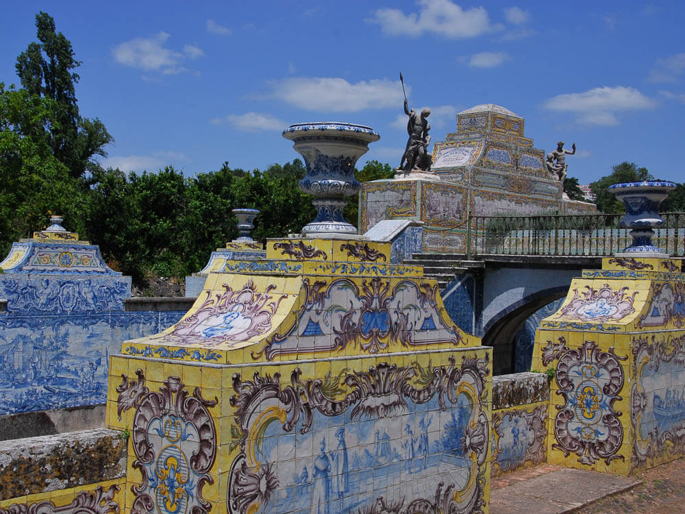 Ornate azulejo tiles at the Palácio da Fronteira, featuring detailed blue and yellow designs with classical motifs.