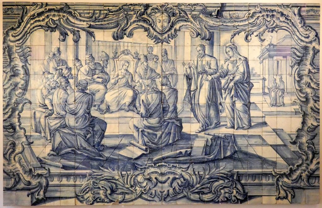 Intricate blue and white azulejo tile artwork depicting a biblical scene with multiple figures, framed by elaborate baroque designs, displayed in the National Tile Museum.