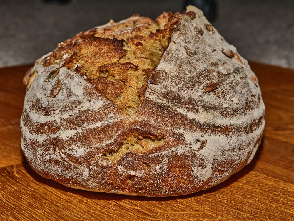 A large, round rye bread on a wooden table.