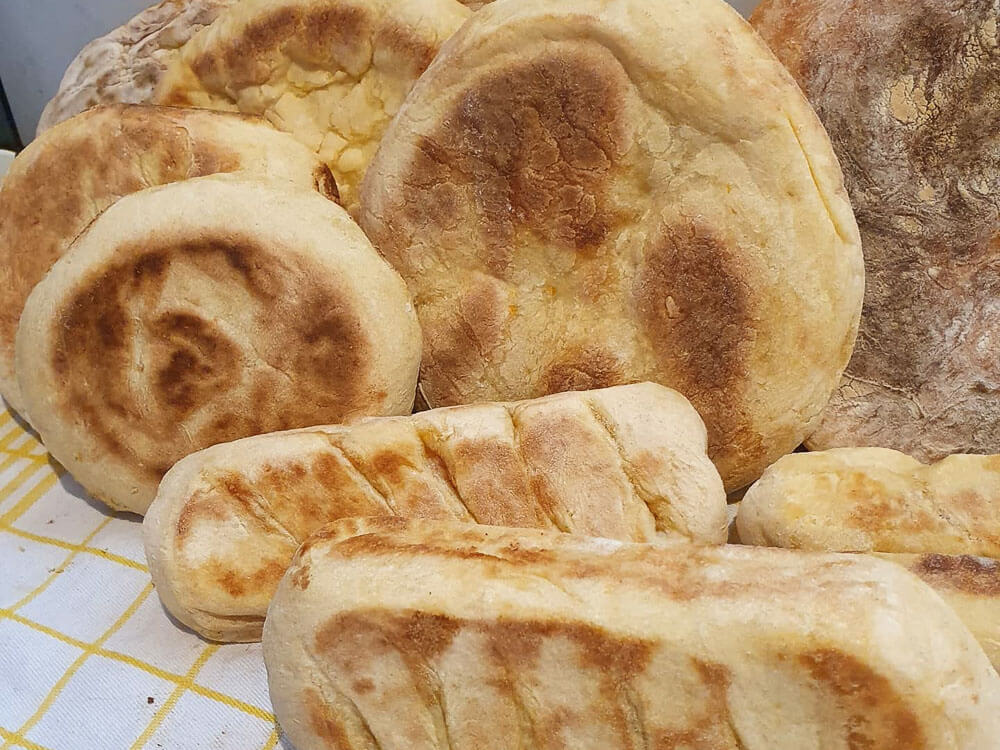 Various types of Bolo do Caco on a yellow and white checkered tablecloth.