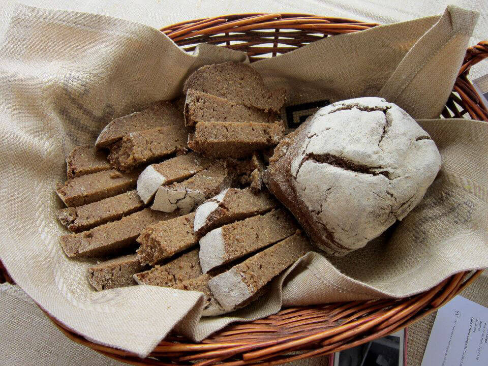 A basket with a beige cloth, inside which there are Avintes broas cut into slices, and one whole.