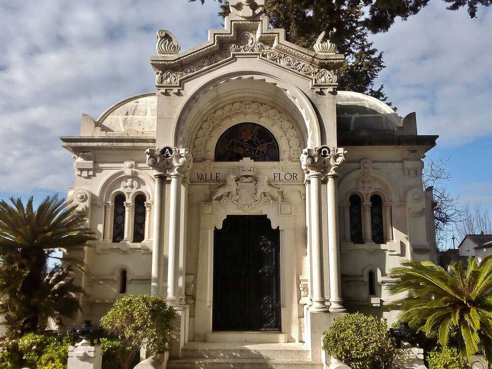 The grand, historic Vale Flor mausoleum in Prazeres Cemetery, featuring elaborate stone carvings and a domed roof.