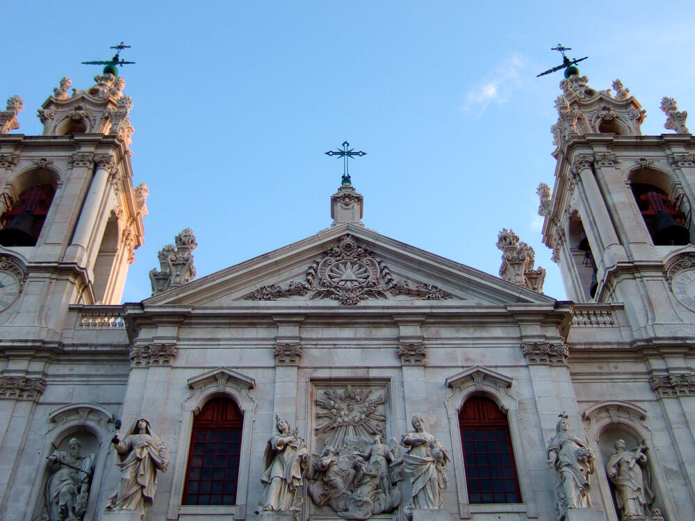 The Basilica da Estrela in Lisbon, with its twin bell towers and ornate facade adorned with statues and intricate carvings.