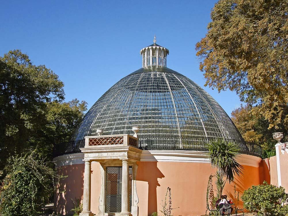 The Estufa Fria, a large greenhouse in Lisbon, characterized by its dome-shaped glass structure set amidst lush greenery.