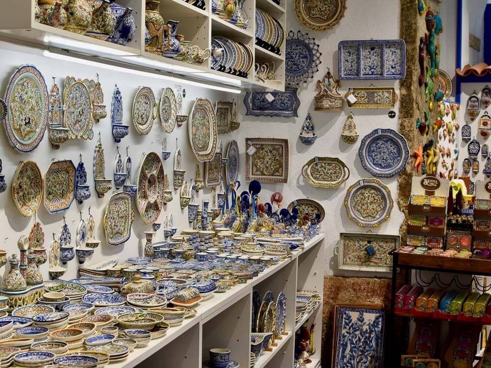 A shop in Lisbon displaying a wide array of colorful azulejo pottery and tiles, showcasing the rich tradition of Portuguese ceramic art.