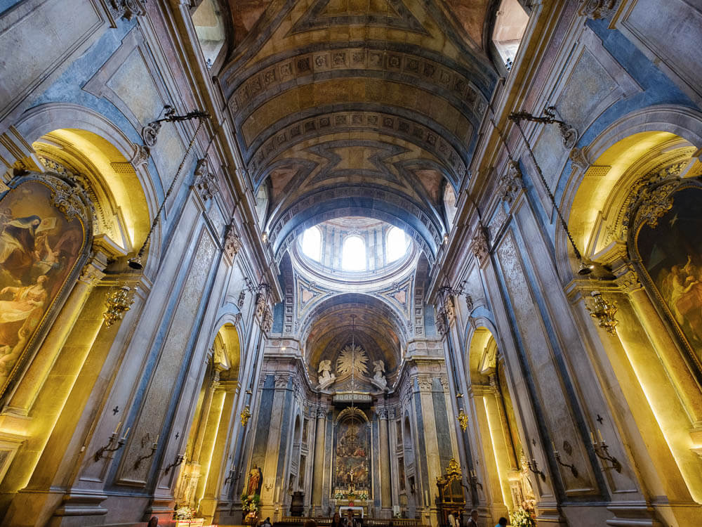 The interior of Basílica da Estrela, looking towards the altar with high arches and painted walls.