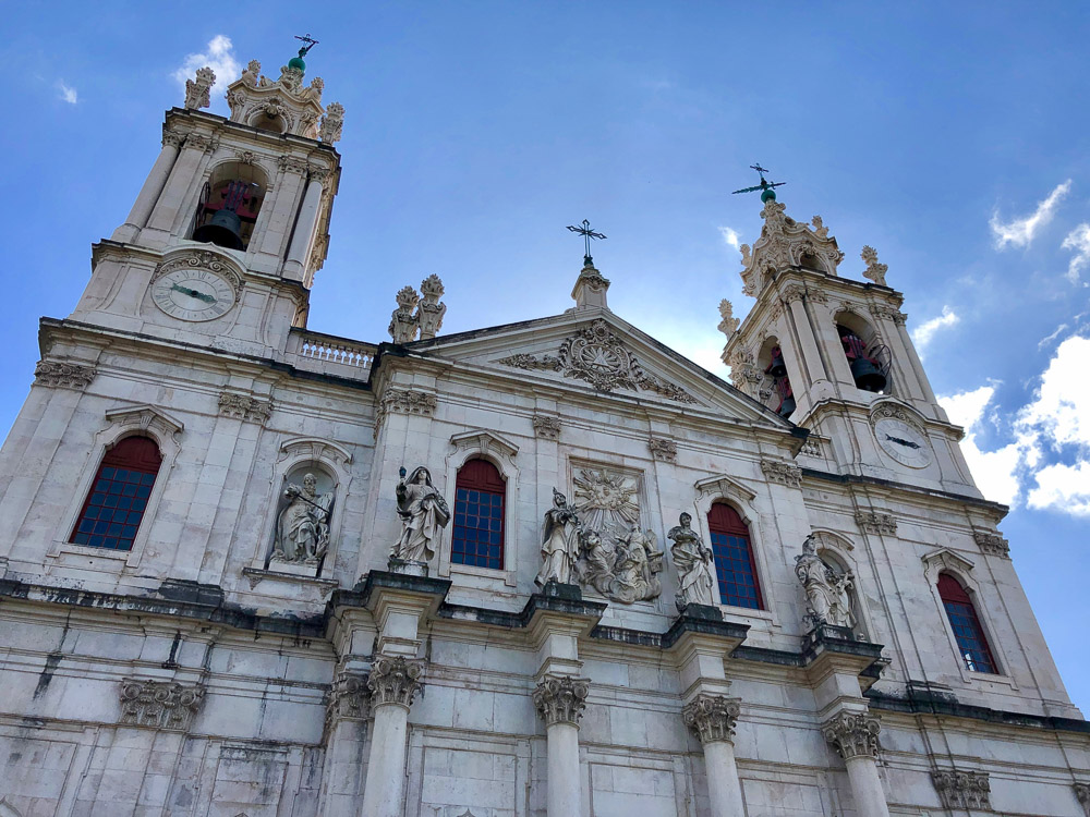 The front facade of Basílica da Estrela with its twin bell towers and statues.