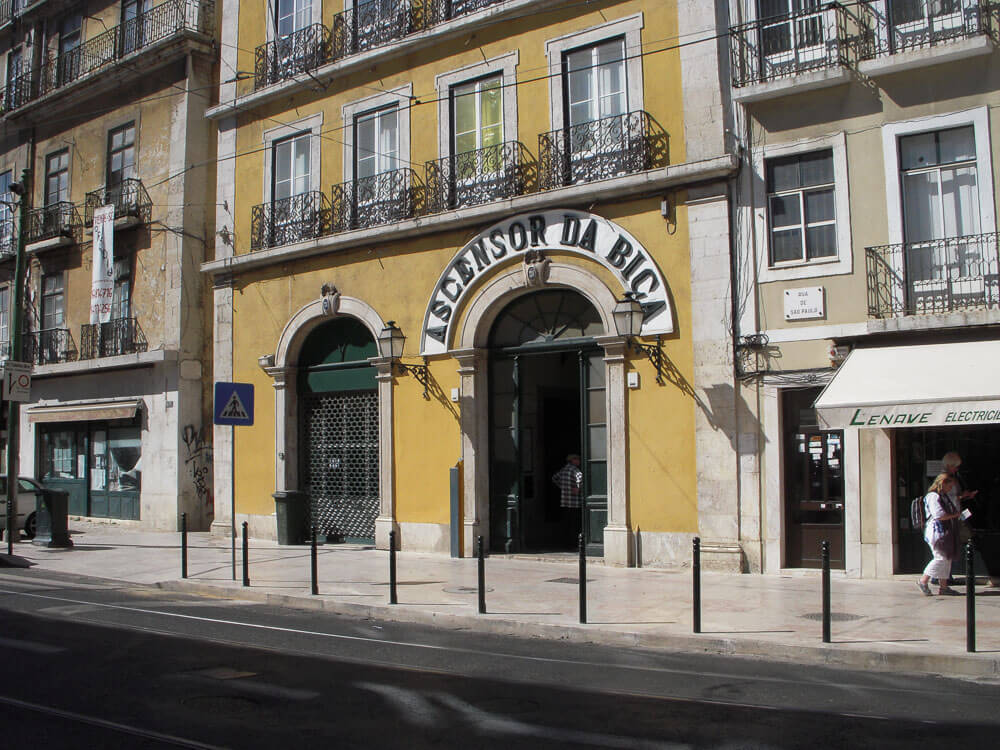 The entrance to the Bica Funicular station in Lisbon, with a yellow building facade.