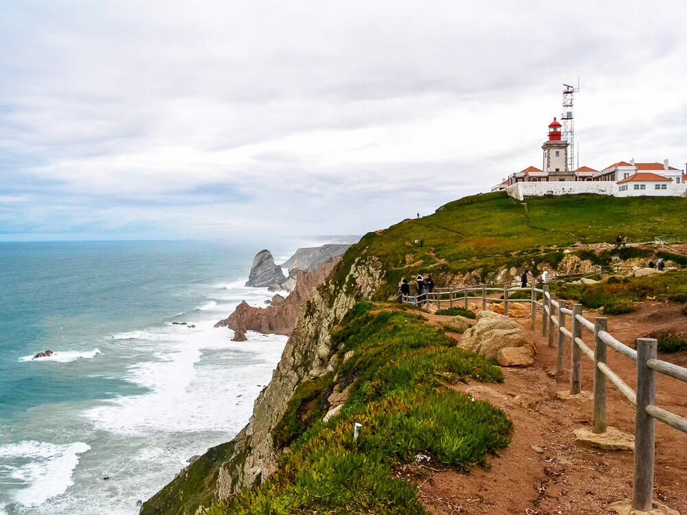 A picturesque scene of a lighthouse perched on a cliff, with a winding path leading up to it and the ocean stretching out in the background.