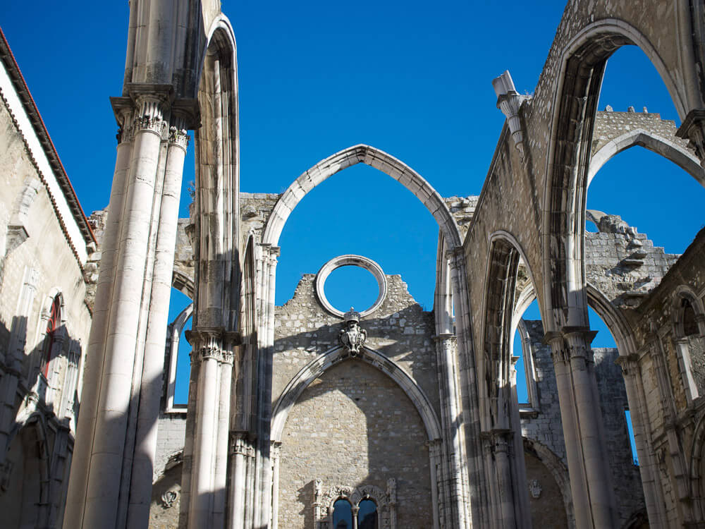 A view of the Carmo Convent arches against a clear blue sky, highlighting the architectural details.