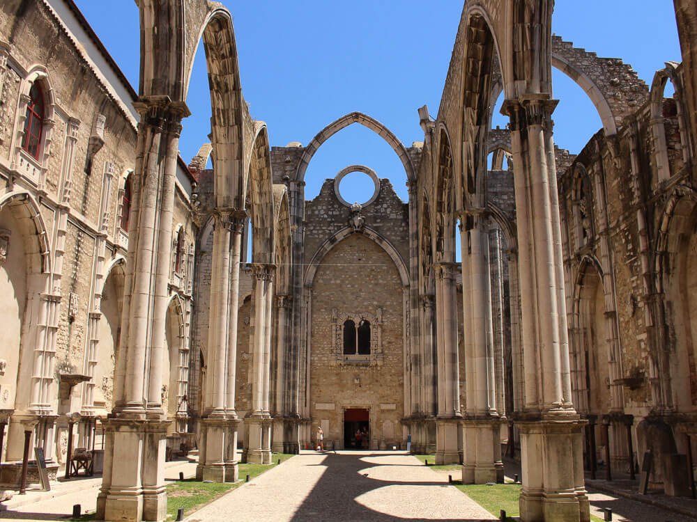 The central aisle of the Carmo Convent with tall, arched columns and a view towards the altar area.