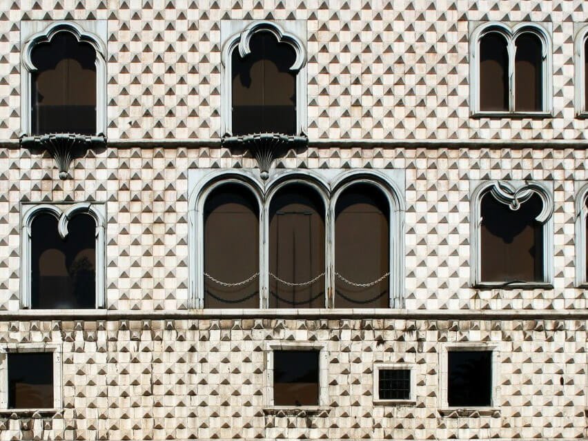 Facade of Casa dos Bicos with its distinctive diamond-shaped stone exterior and arched windows.