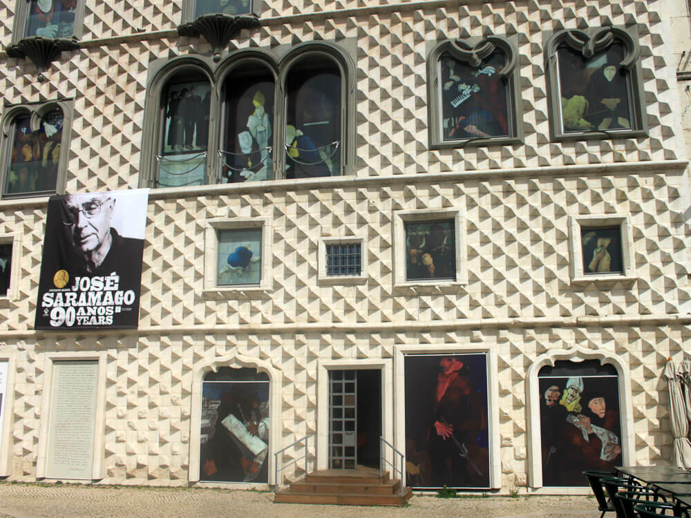 Casa dos Bicos facade with a banner of José Saramago displayed, highlighting the building's architectural details.