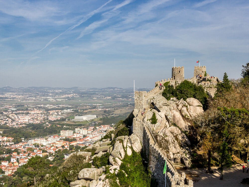 A stone fortress on a hill, offering a panoramic view of a town and surrounding landscape.