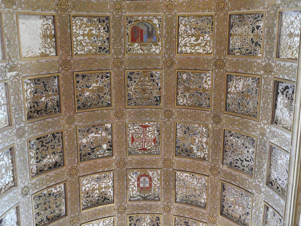 Intricately decorated ceiling with geometric patterns and gold details, featuring various symbols and religious motifs.