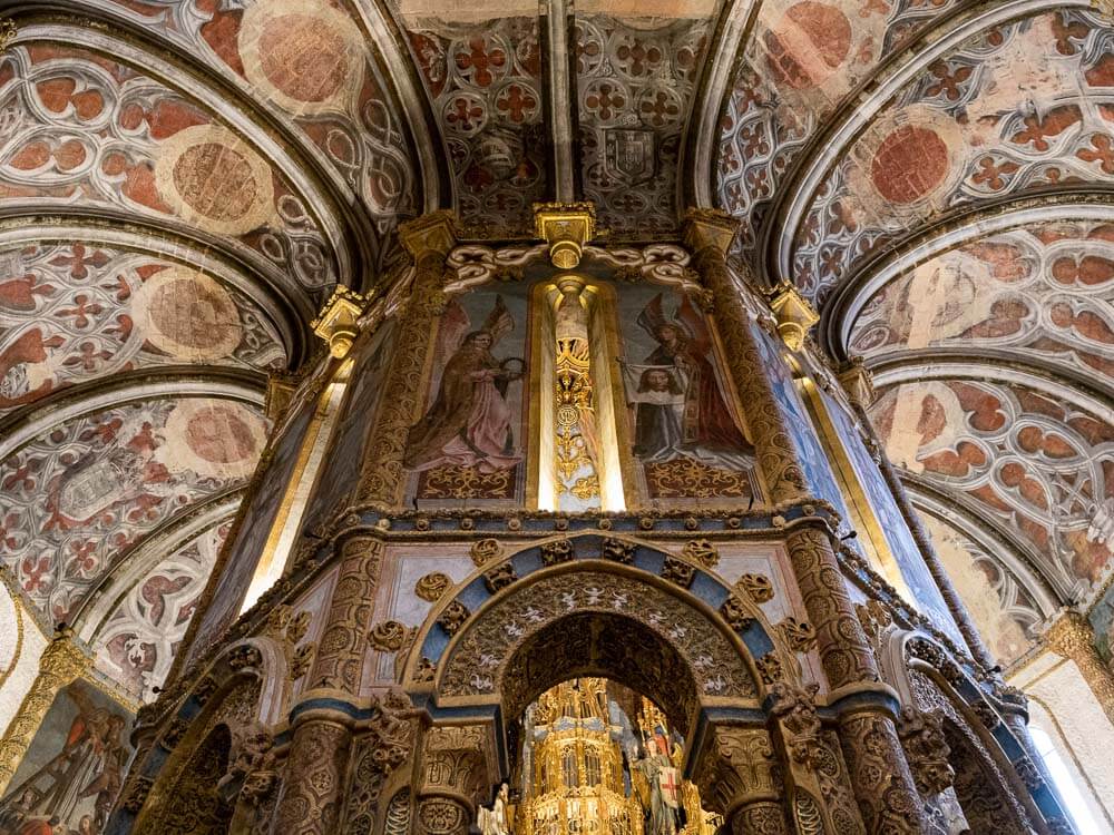 Interior view of the Convent of Christ, showcasing the intricate painted ceiling and detailed religious artwork.