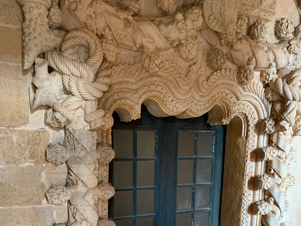 Close-up of an ornate doorway inside the Convent of Christ, adorned with carved rope motifs and other detailed stonework.