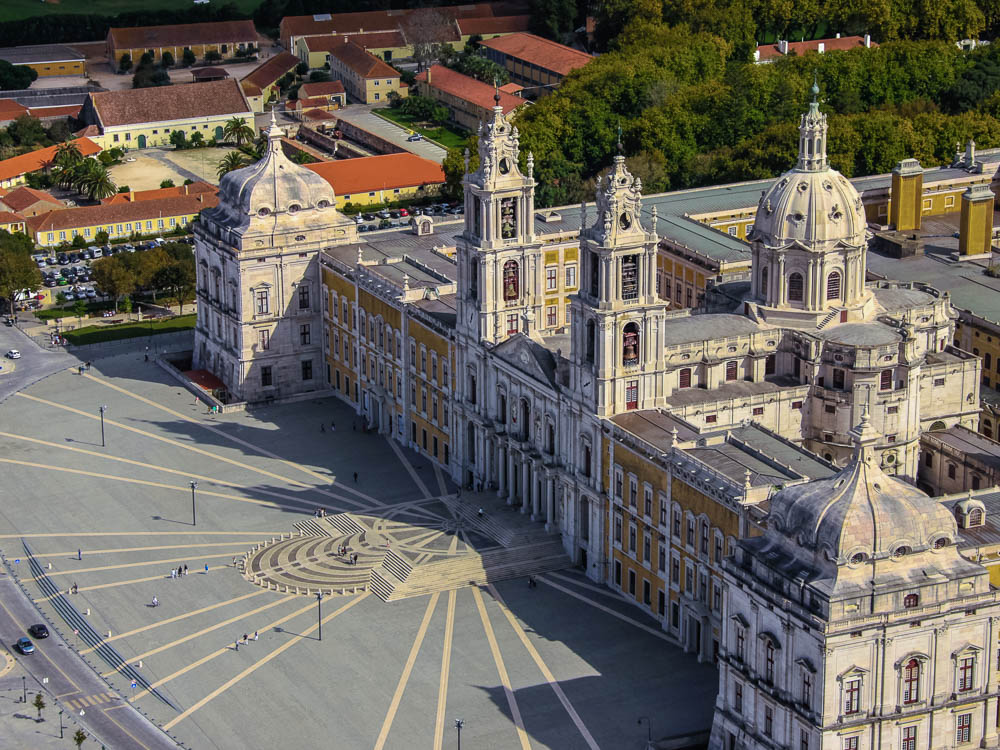 Aerial view of the grand Mafra Palace, an 18th-century Baroque and Neoclassical palace, with its impressive facade and expansive courtyard.