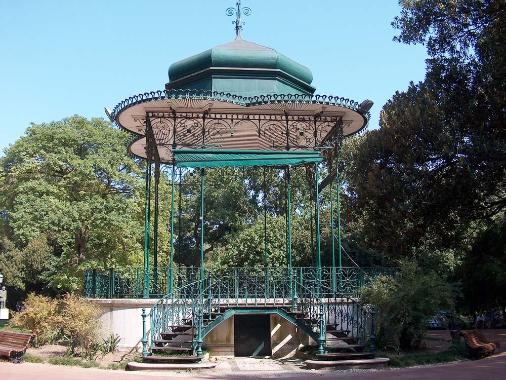 A green iron gazebo surrounded by trees in Jardim da Estrela park.