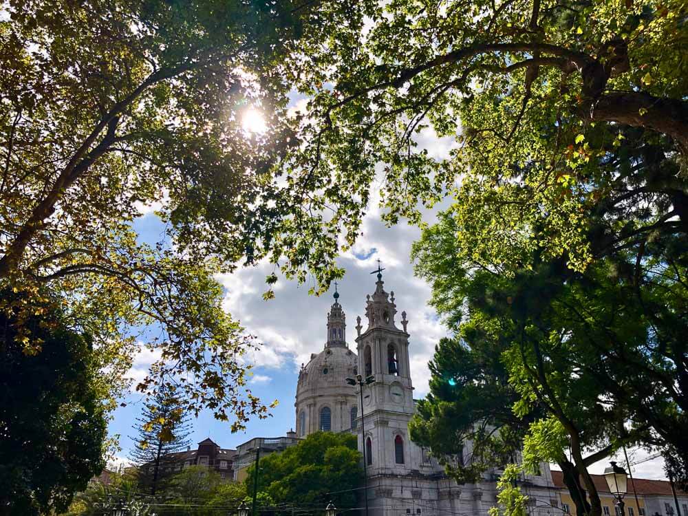 The twin towers of the Basílica da Estrela visible through the trees in Jardim da Estrela park.