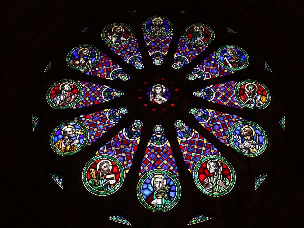 Detailed view of a circular stained glass window with various colorful religious scenes.