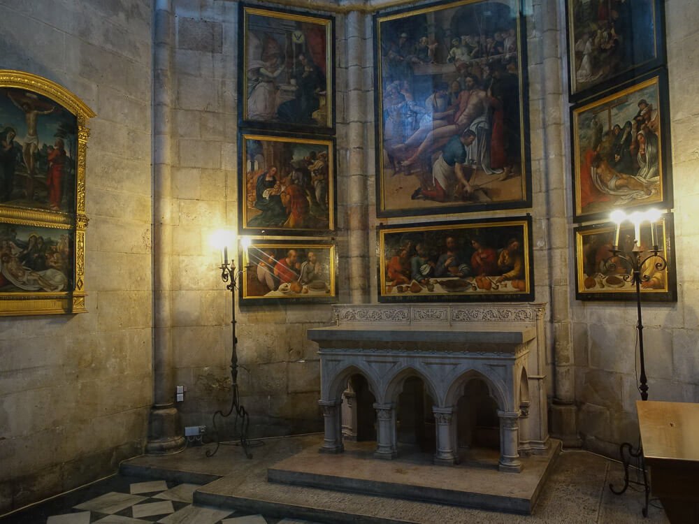 Interior of a chapel featuring a small altar surrounded by religious paintings.