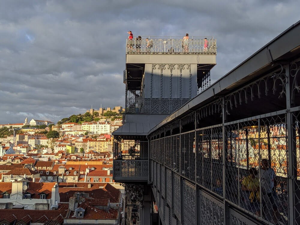 The top platform of the Santa Justa Lift with people enjoying views of the city, with Lisbon’s rooftops and landmarks visible in the background.