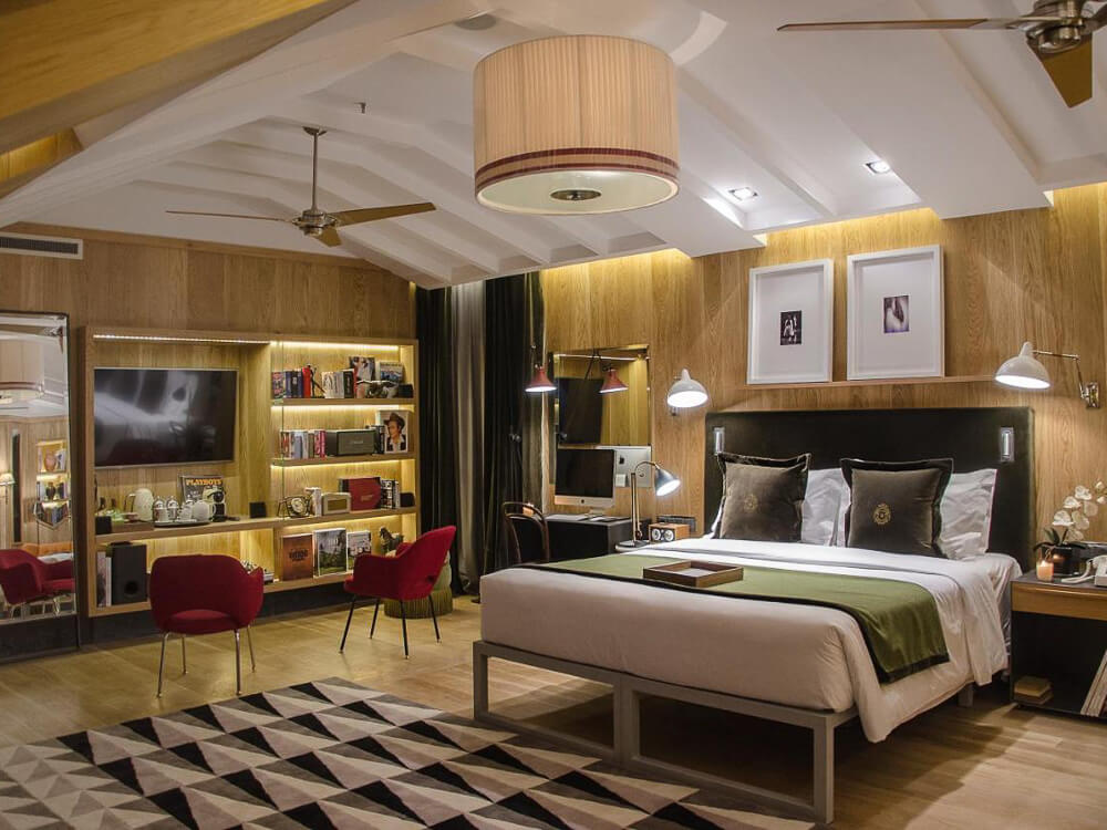 Modern boutique hotel room with a sleek design, wood accents, and a well-lit bookshelf in Lisbon.