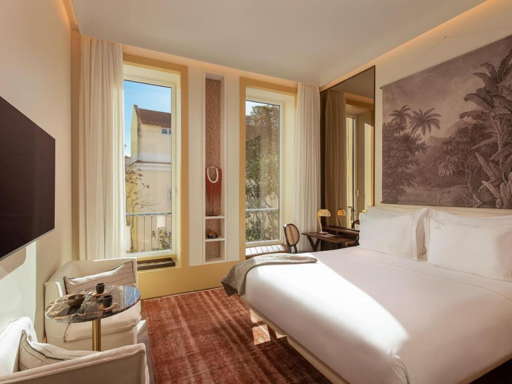 Stylish boutique hotel room with large windows, minimalist decor, and a wall mural in Lisbon.