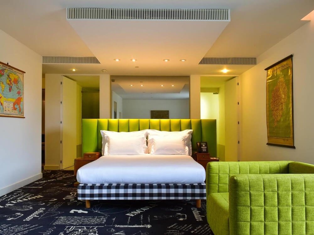 Bright and modern hotel room with vibrant green accents, featuring a green headboard, matching furniture, and unique décor.